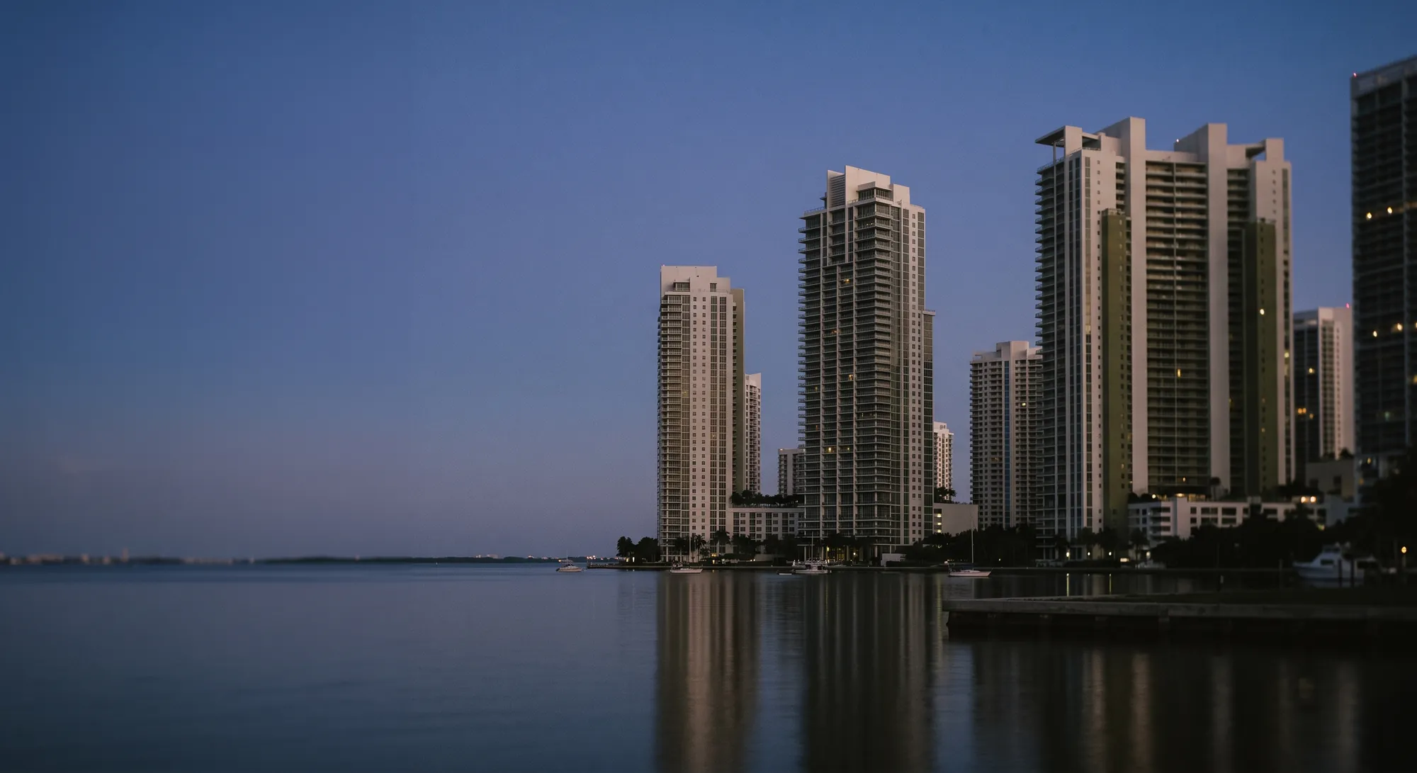 Luxury residential towers reflected on calm water at dusk